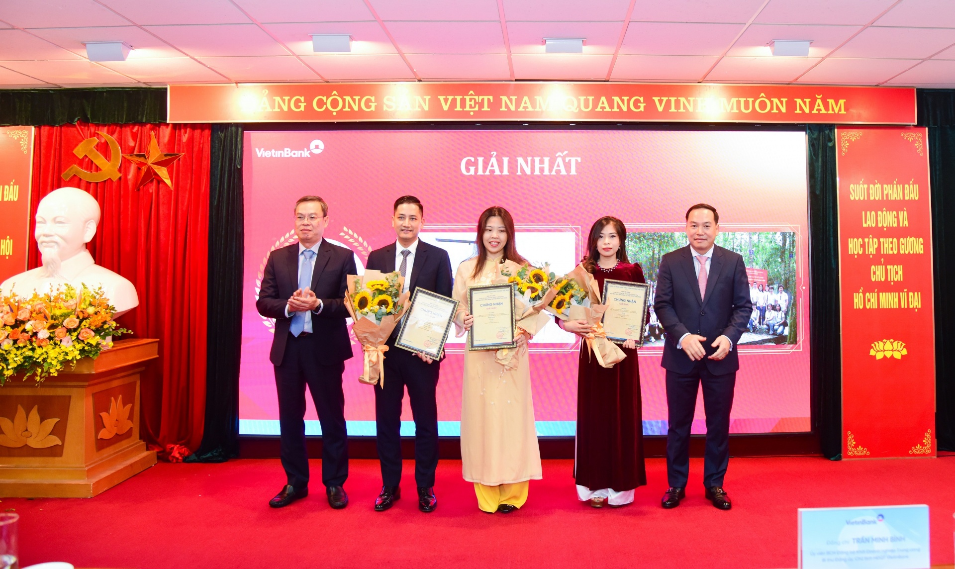 Đồng chí Hồ Xuân Trường - Phó Bí thư Đảng ủy Khối DNTW (bên phải) và đồng chí Trần Minh Bình - Ủy viên Ban Chấp hành Đảng bộ Khối DNTW, Bí thư Đảng ủy, Chủ tịch Hội đồng quản trị NHCTVN (bên trái) trao Giấy chứng nhận và hoa cho các tác giả/nhóm tác giả đạt giải Nhất.