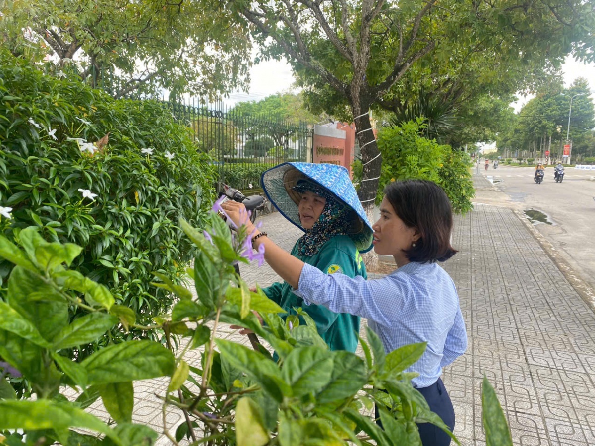 Chị Thịnh hướng dẫn công nhân cách chăm sóc cây xanh. Ảnh: Hoài Nam