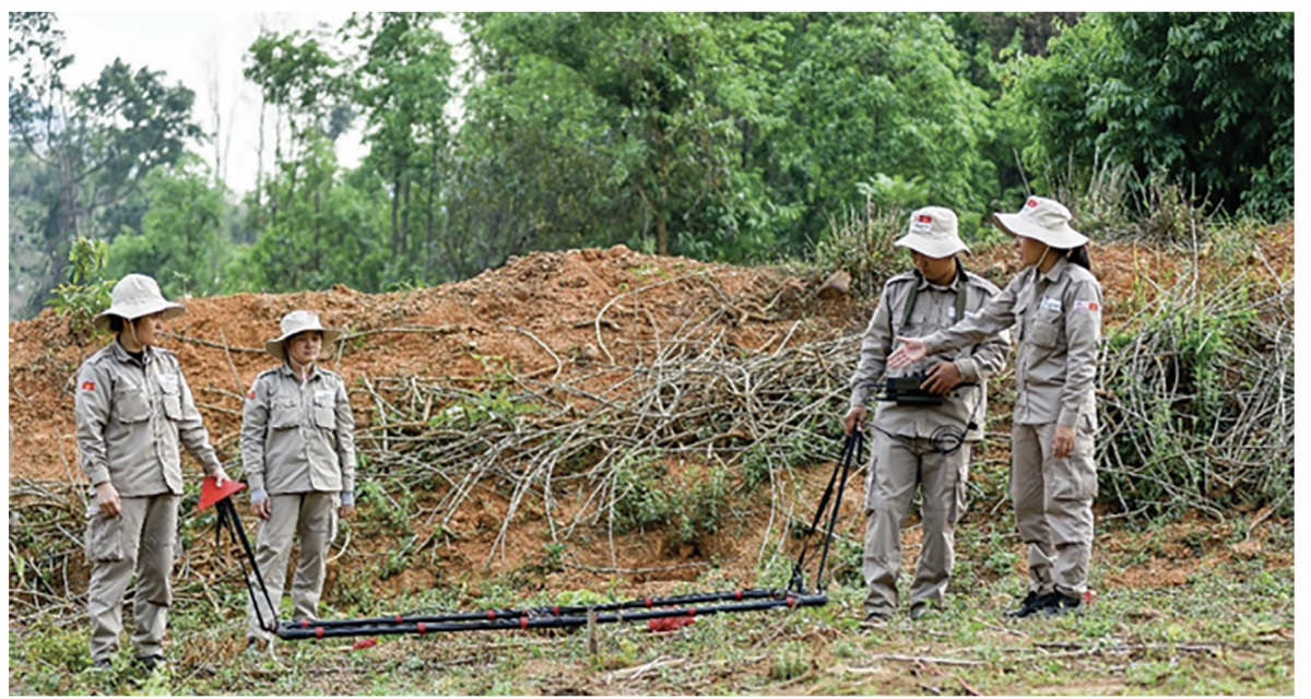 Chị Nguyễn Thị Lệ Khuyên (ngoài cùng bên phải) đang nhắc nhở lại các thành viên trong nhóm chú ý làm đúng các thao tác kỹ thuật trước khi tiến hành rà phá bom mình. Ảnh: TGCC.