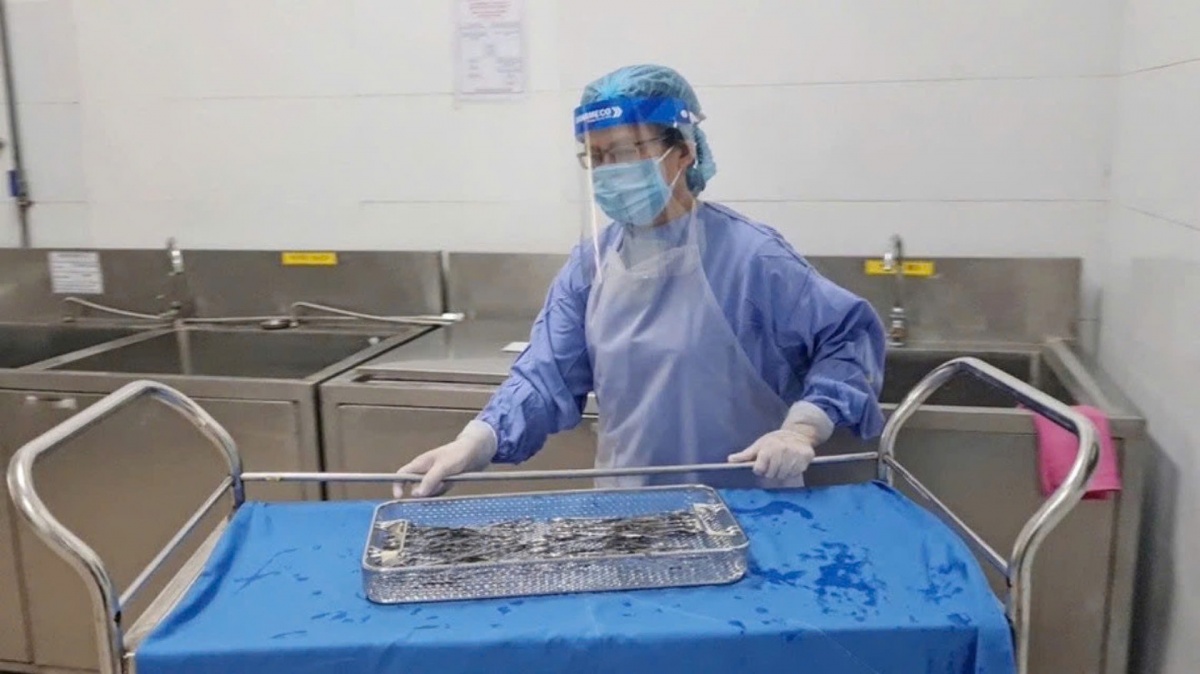 Nhân viên kiểm soát nhiễm khuẩn tiếp nhận và xử lý dụng cụ y tế sau sử dụng tại khu vực bẩn, khâu này yêu cầu tuân thủ nghiêm ngặt phương tiện phòng hộ cá nhân và quy trình xử lý dụng cụ. Ảnh: NAM BÌNH.