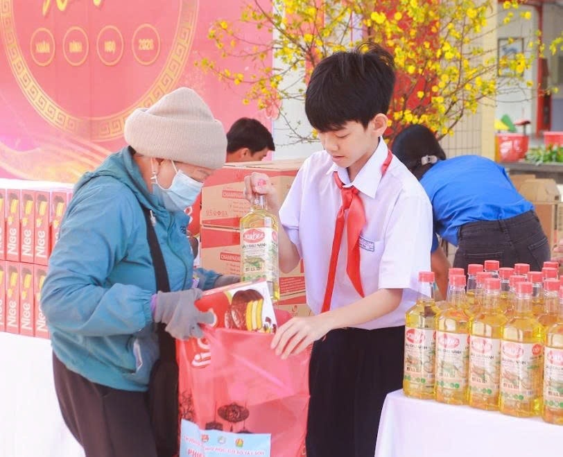 Em Ngô Đức Tuấn Kiệt, học sinh Trường Tiểu học Tây Sơn cẩn thận trao quà cho người dân có hoàn cảnh khó khăn. Ảnh: HỮU TRUNG