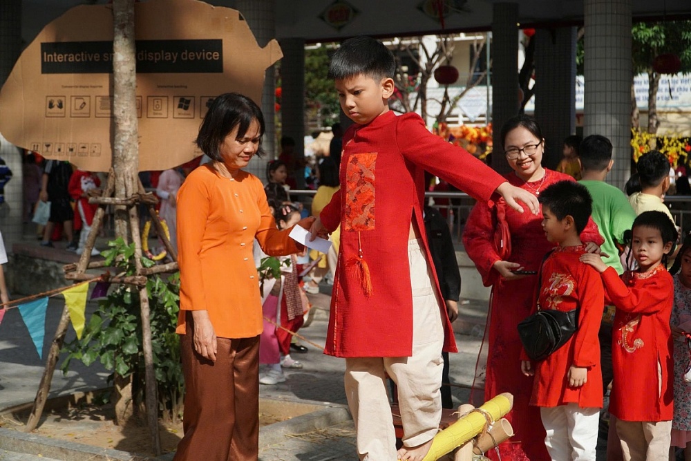 Gia đình chị Hoàng Thị Ngọc Mai (phường Hòa Cường) diện áo dài đồng điệu, hào hứng trải nghiệm trò chơi dân gian. Ảnh: HỮU TRUNG