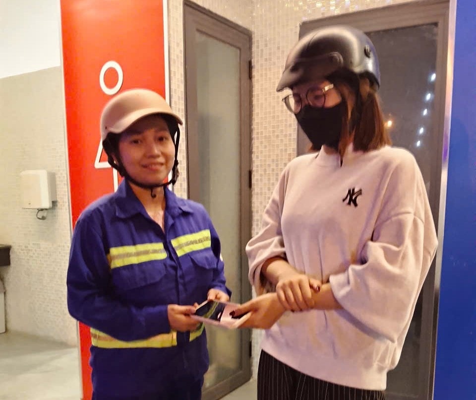 Chị Trần Vũ Hạ Lan, công nhân Đội môi trường Hòa Cường thuộc Công ty CP Môi trường đô thị Đà Nẵng (bên trái) trao trả tài sản cho du khách. Ảnh do nhân vật cung cấp